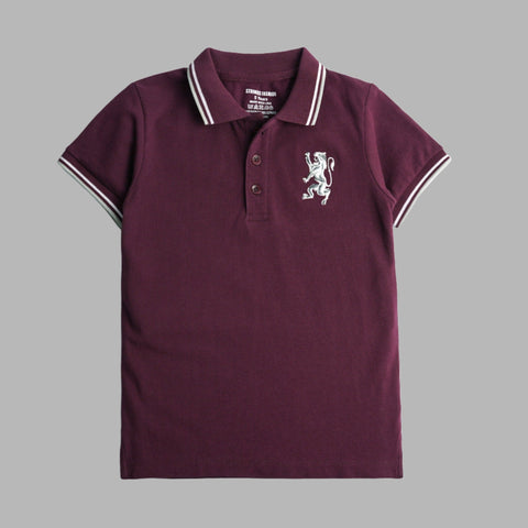A burgundy short sleeve polo t-shirt for boys with a white collar and a white embroidered emblem on the chest.