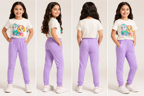 Young girl modeling a white t-shirt with a cartoon design and purple pants in front of a plain background.