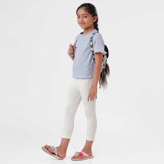 A young girl wearing white leggings and a grey t-shirt, standing against a white background. 543